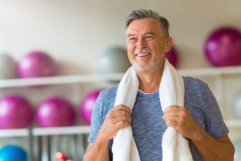 smiling older man in gym with towel around shoulders