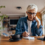 Mature woman, taking notes during a free online course on her tablet