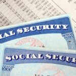 Two Social Security cards laying over a sheet of paper of retirement income, Social Security and Medicare work together to support you in retirement