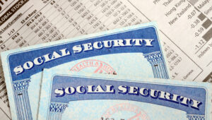 Two Social Security cards laying over a sheet of paper of retirement income, Social Security and Medicare work together to support you in retirement