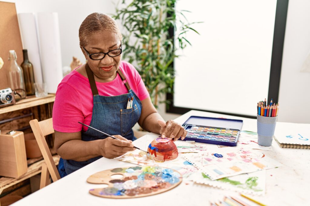 Senior African American woman painting clay ceramic at art studio, just one of her new hobbies