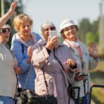 Group of women on one of several senior tours take a self-portrait on a platform waiting for a train to travel