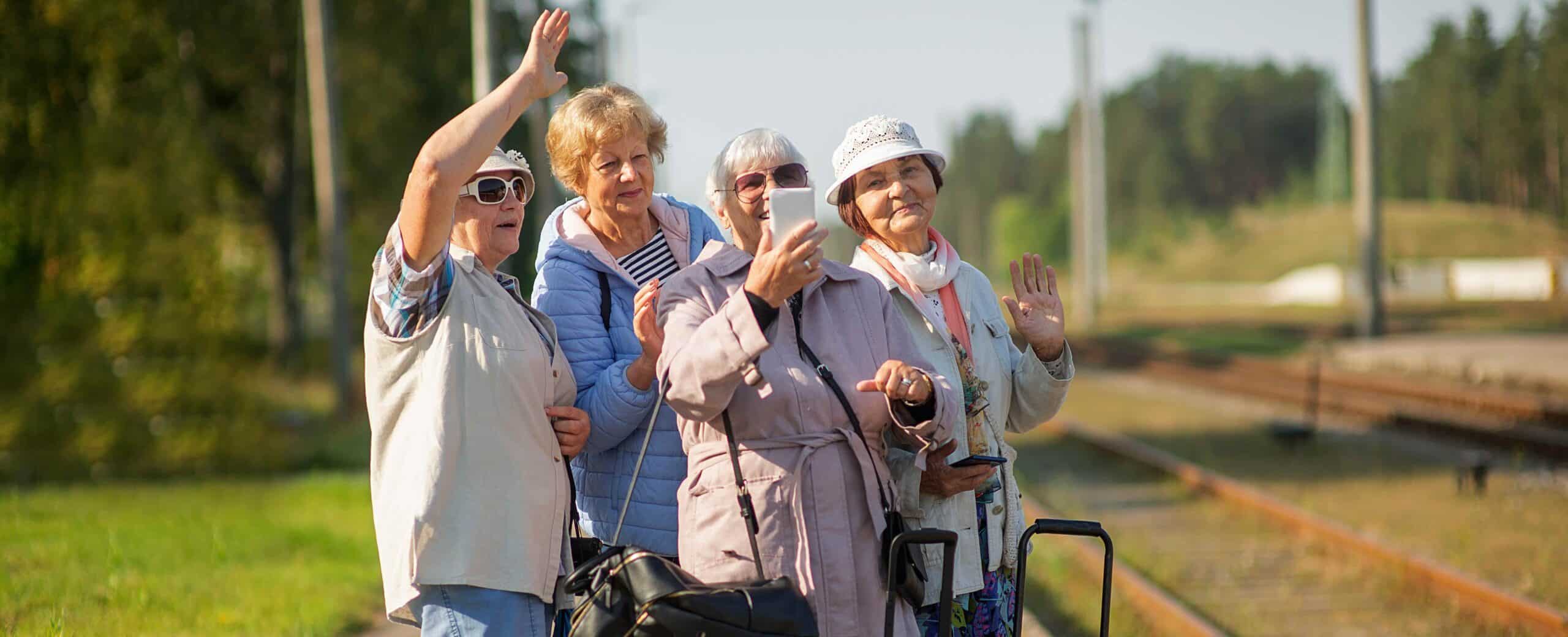 Group of women on one of several senior tours take a self-portrait on a platform waiting for a train to travel