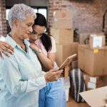 Shot of a senior woman looking at a photograph with her daughter while packing boxes on moving day. Moving and losing your existing coverage may be eligible for guaranteed issue rights.