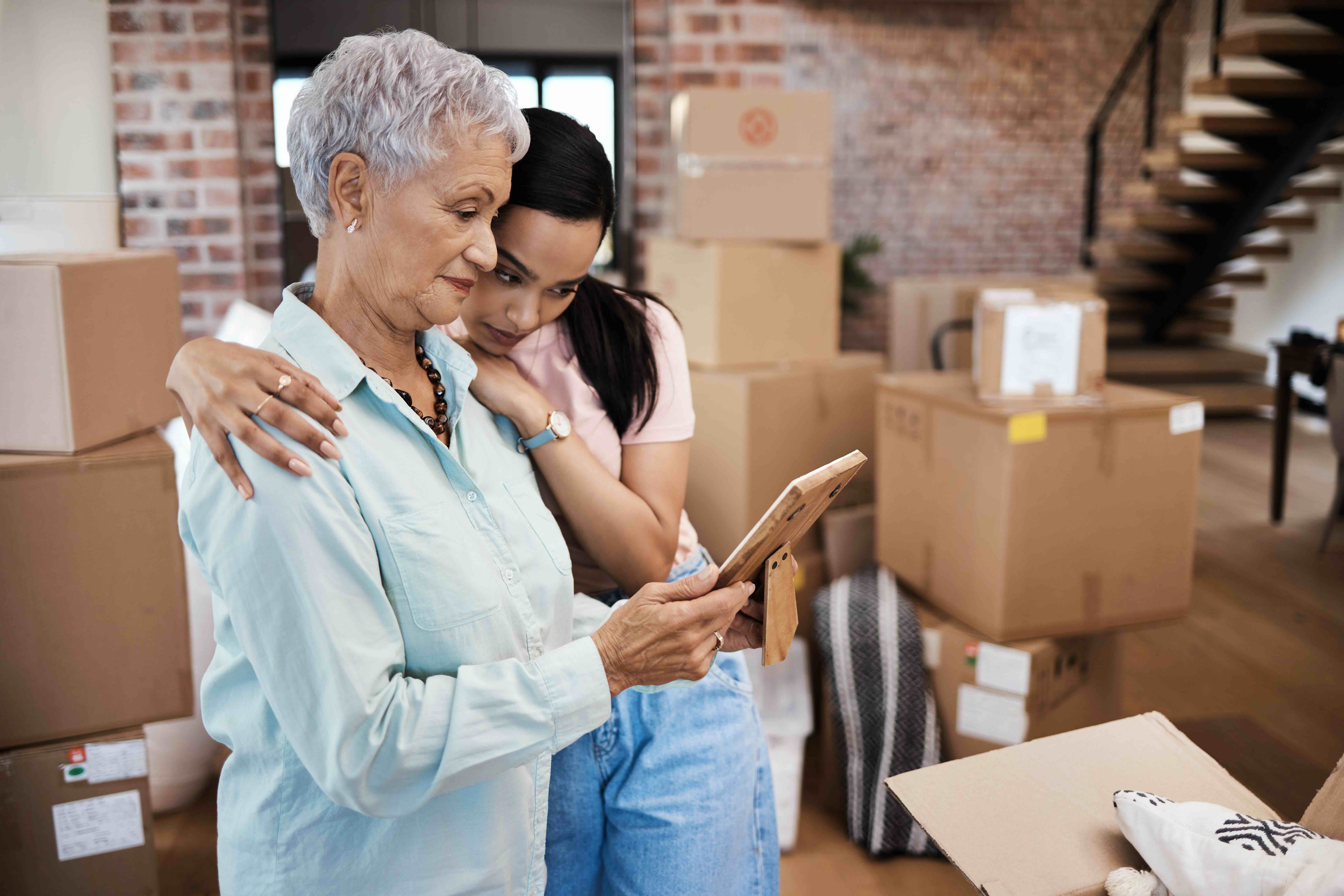 Shot of a senior woman looking at a photograph with her daughter while packing boxes on moving day. Moving and losing your existing coverage may be eligible for guaranteed issue rights.