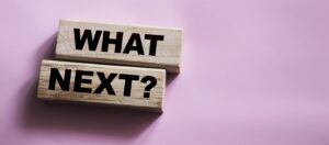 The words What Next on wooden blocks, close up shot, view from above. Next steps concept for business or Medicare changes