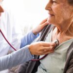 Health visitor and a senior woman during home visit. A nurse or a doctor examining a woman. Close up as a concept of coverage for Medicare Supplement preventive care.