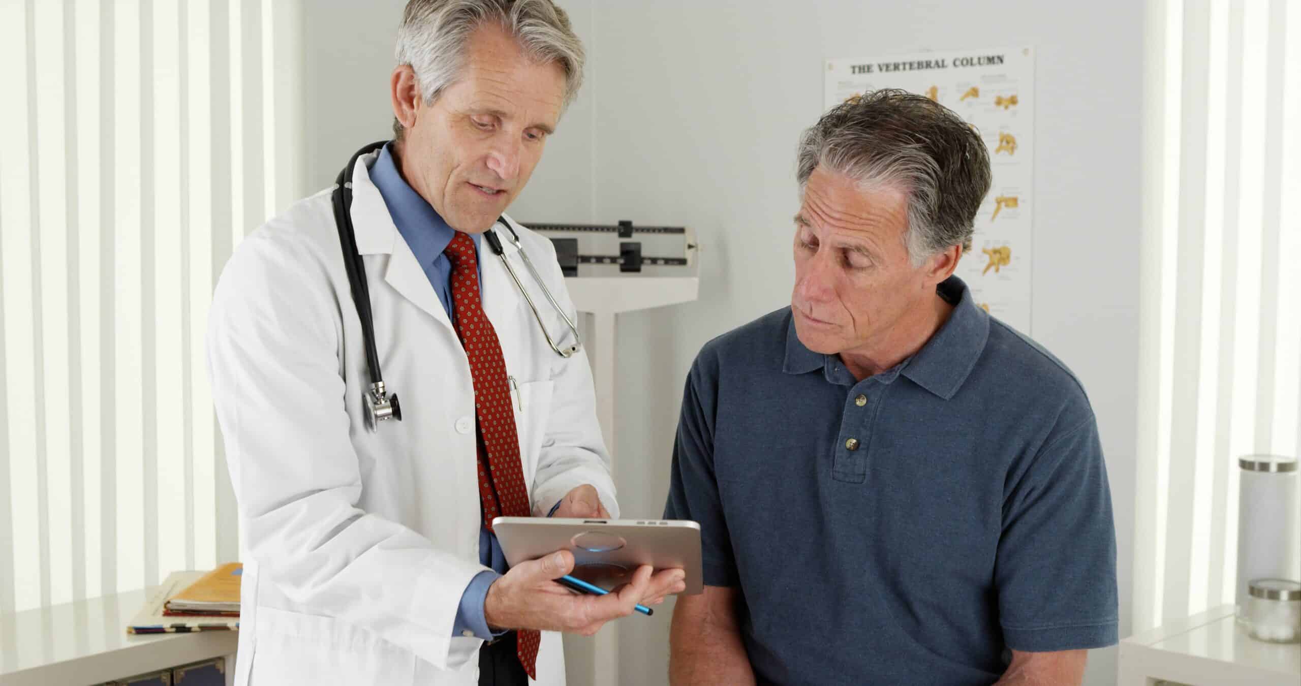 A male doctor shows a questionnaire to an older male patient. These series of questions are an important part of a Medicare annual wellness visit.
