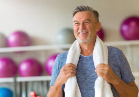 smiling older man in gym with towel around shoulders