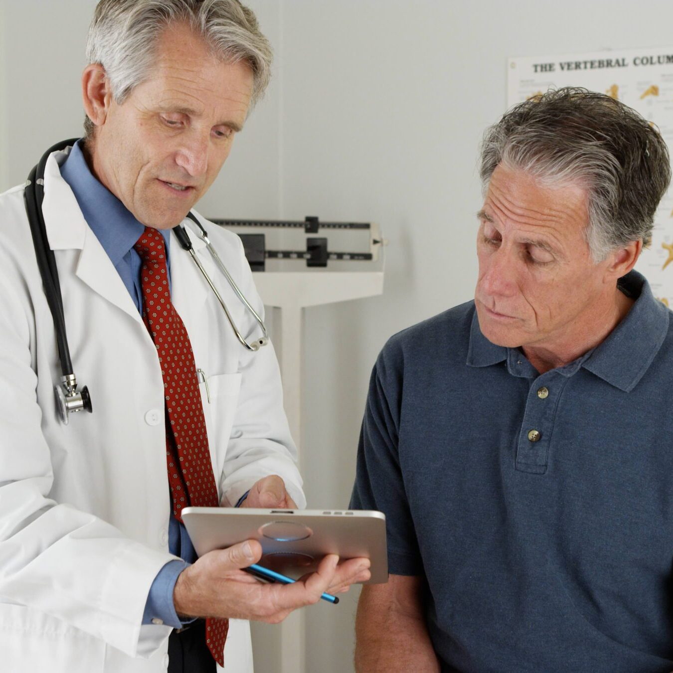 A male doctor shows a questionnaire to an older male patient. These series of questions are an important part of a Medicare annual wellness visit.